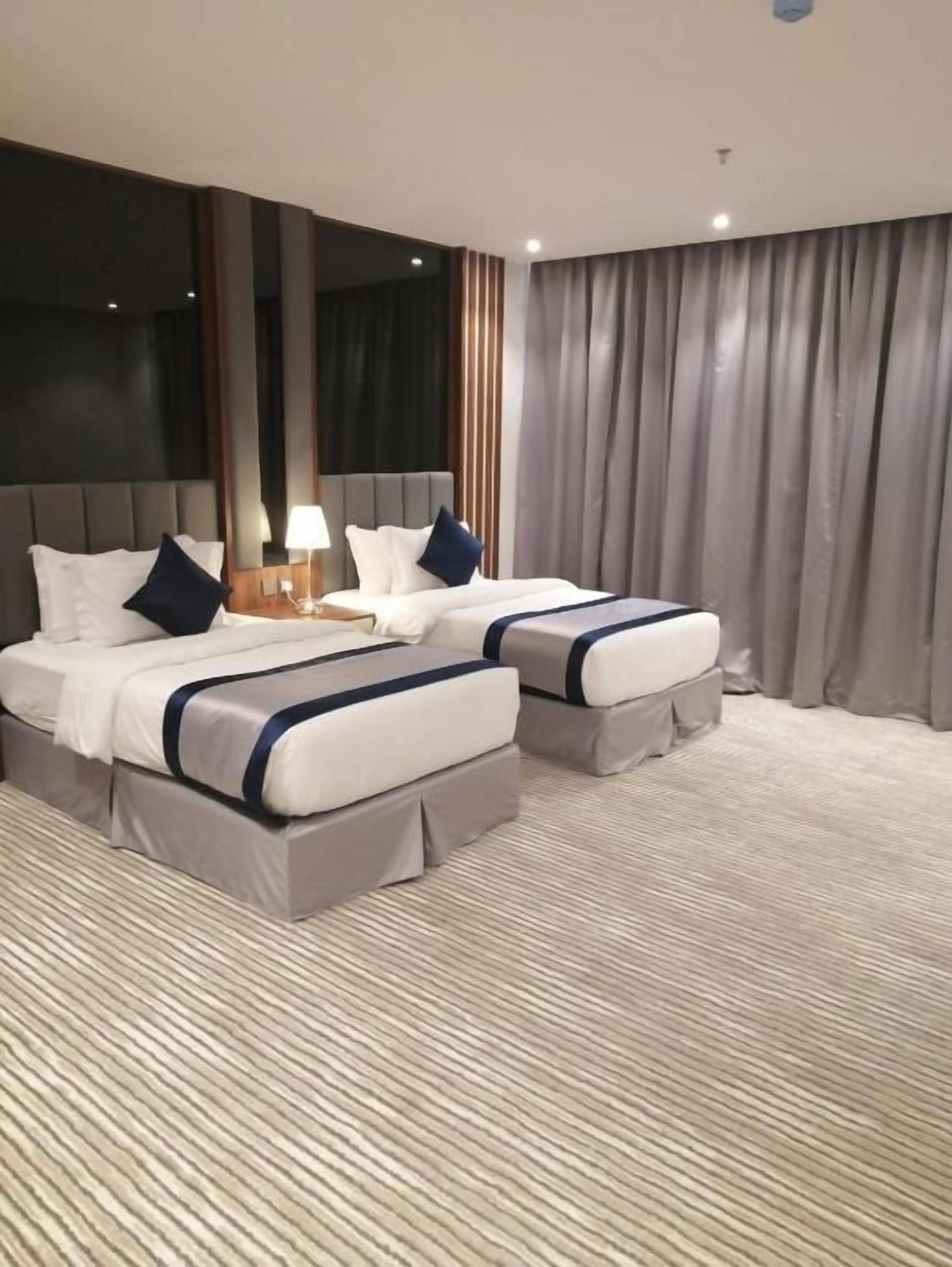 Habitación de hotel con dos camas, un espejo grande y vistas a la ciudad.