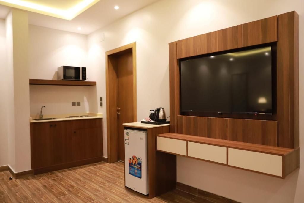 Una cocina compacta con televisión integrada, microondas y refrigerador pequeño.