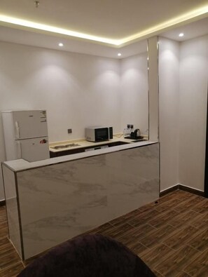 A modern kitchen with a marble countertop, a refrigerator, a microwave, and a sink. - Tulip View Hotel (Khamis Mushait)