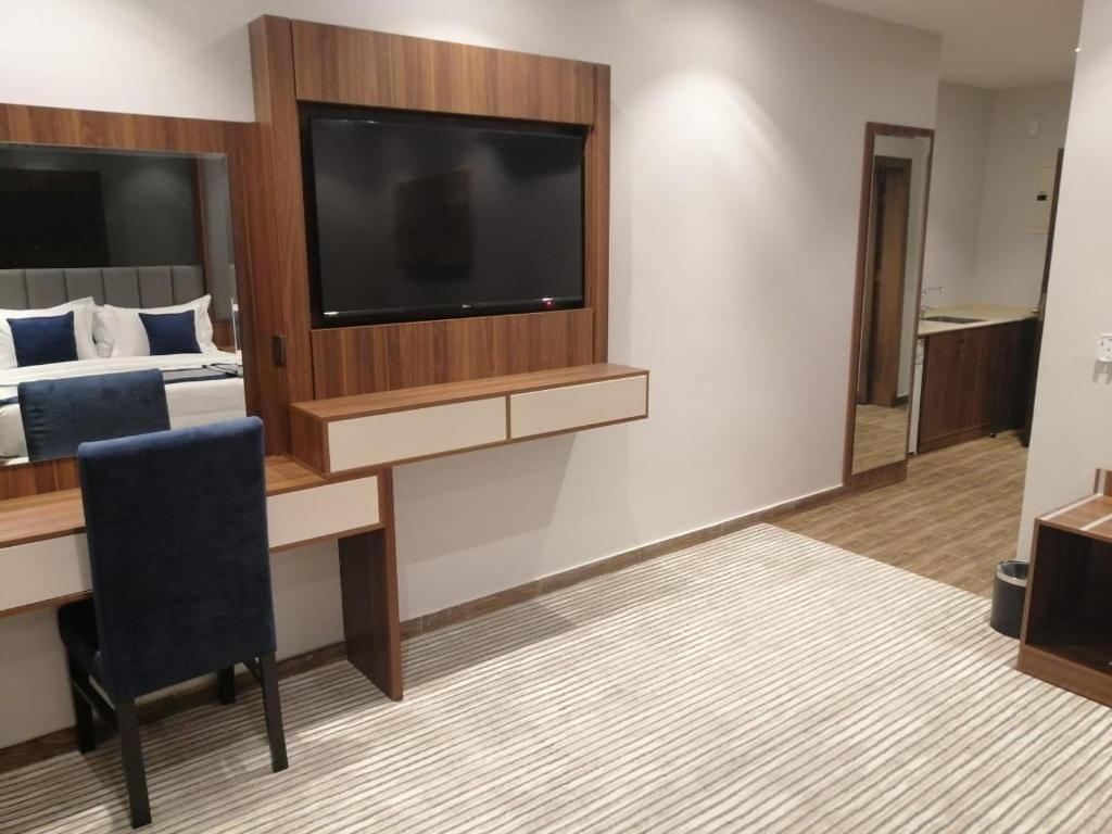 Un dormitorio moderno con una cama, un escritorio y una televisión montada en la pared.