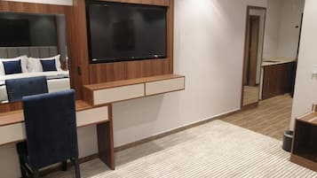 Un dormitorio moderno con una cama, un escritorio y una televisión montada en la pared.