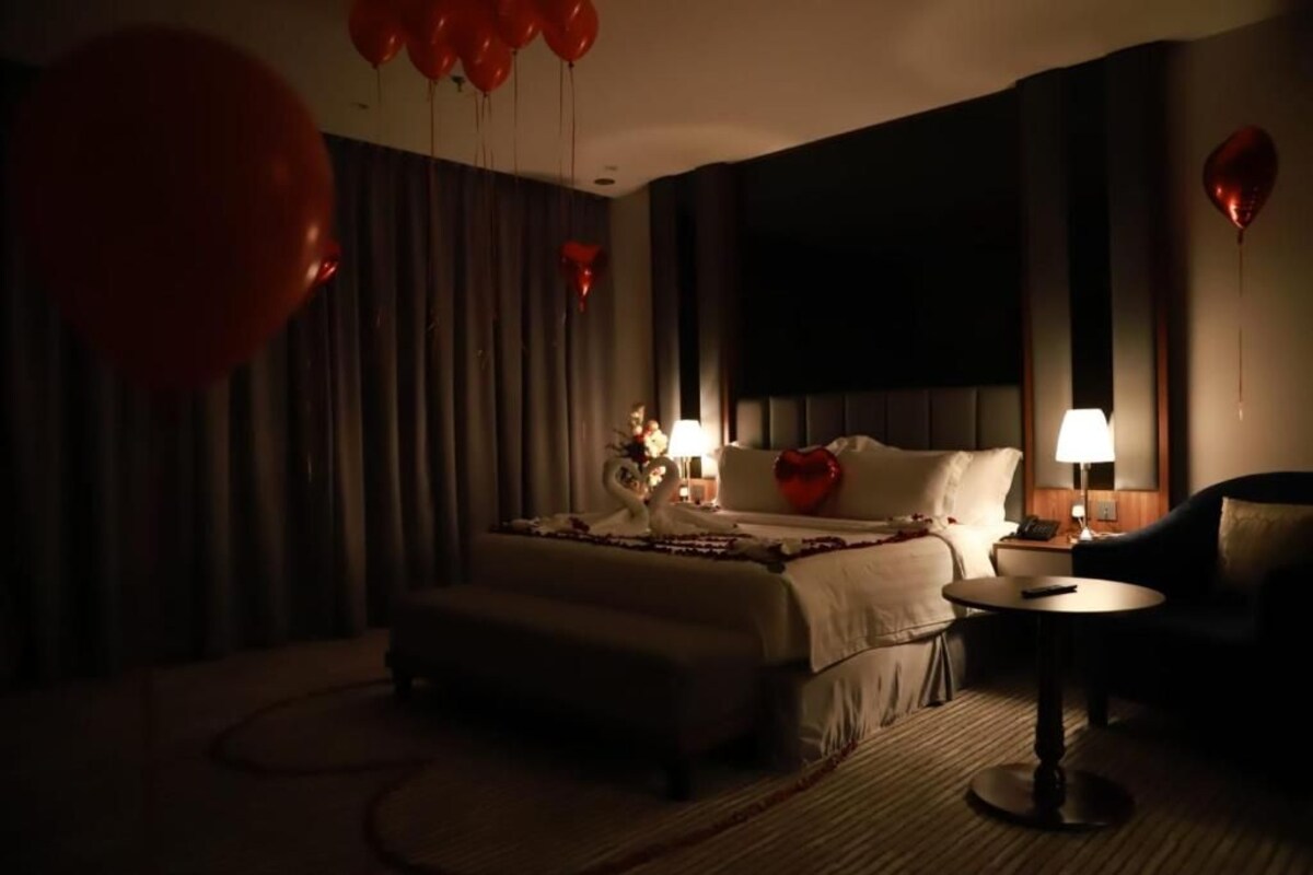 A hotel room with a bed, bedside tables, a round table, and a sofa.