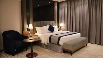 A hotel room with a large bed, a bedside table, a chair, and a lamp.