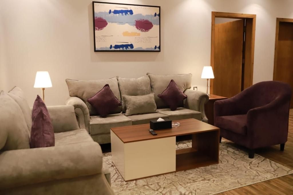 A living room with a sofa, armchairs, a coffee table, and a painting on the wall.