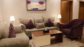 A living room with a sofa, armchairs, a coffee table, and a painting on the wall.