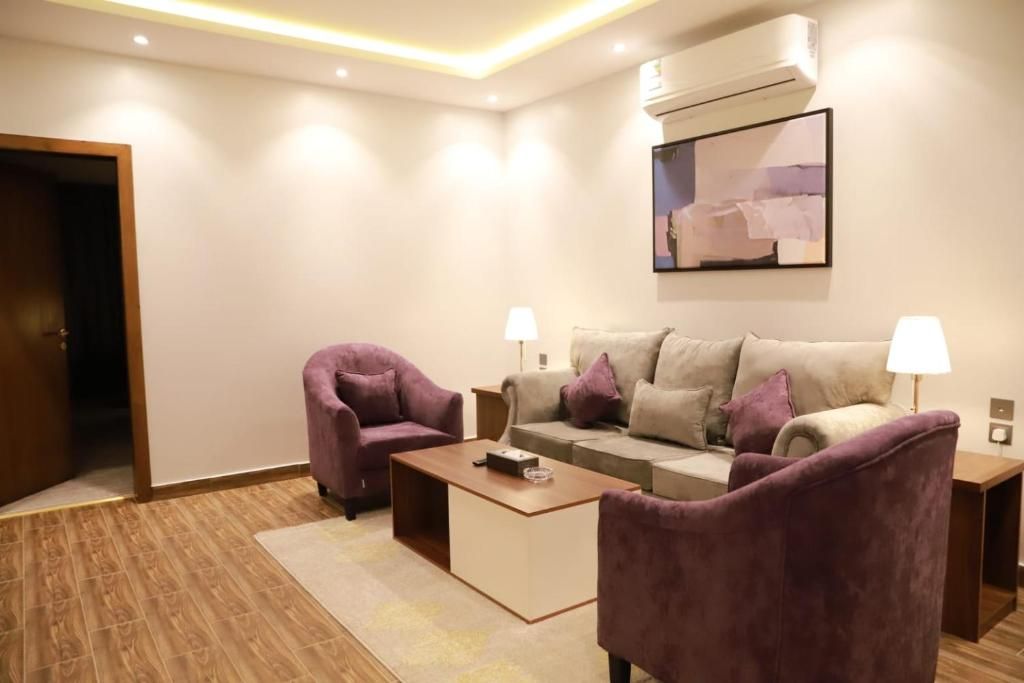 Een moderne woonkamer met een bank, twee fauteuils, een salontafel en een televisie.