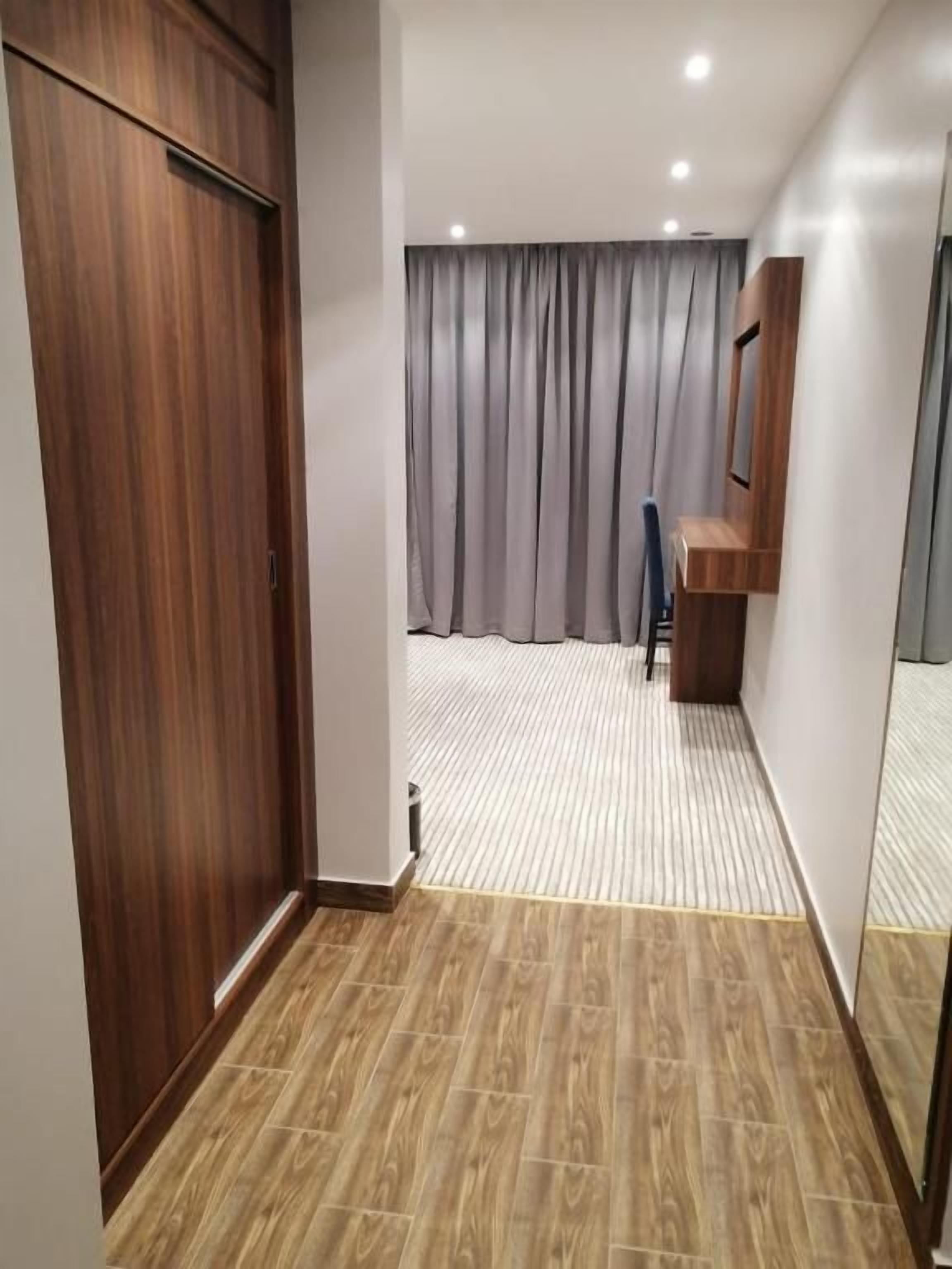 Un corridoio con un'armadiatura in legno, una tenda grigia e una panca di legno.