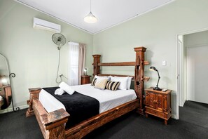 Ein traditionelles Bett mit Holzkopfteil, ein Nachttisch mit Lampe und eine Wand-Klimaanlage.