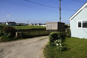 Eine ländliche Straße führt zu einem Haus mit umzäunter Wiese und einem Schuppen.