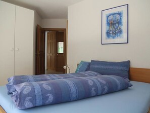 Ein Schlafzimmer mit einem Bett, einer Tür und einem gerahmten Bild an der Wand.