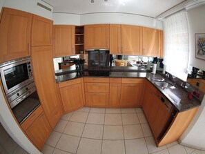 A kitchen with wooden cabinets, a black countertop, and stainless steel appliances. - Edelweiss B 13 # 4-bed apartment, Dusche, WC 4-bed apartment, Dusche, WC by Interhome (Leukerbad)