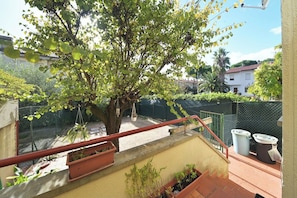 Un balcone con un albero, una ringhiera e piante in vaso.