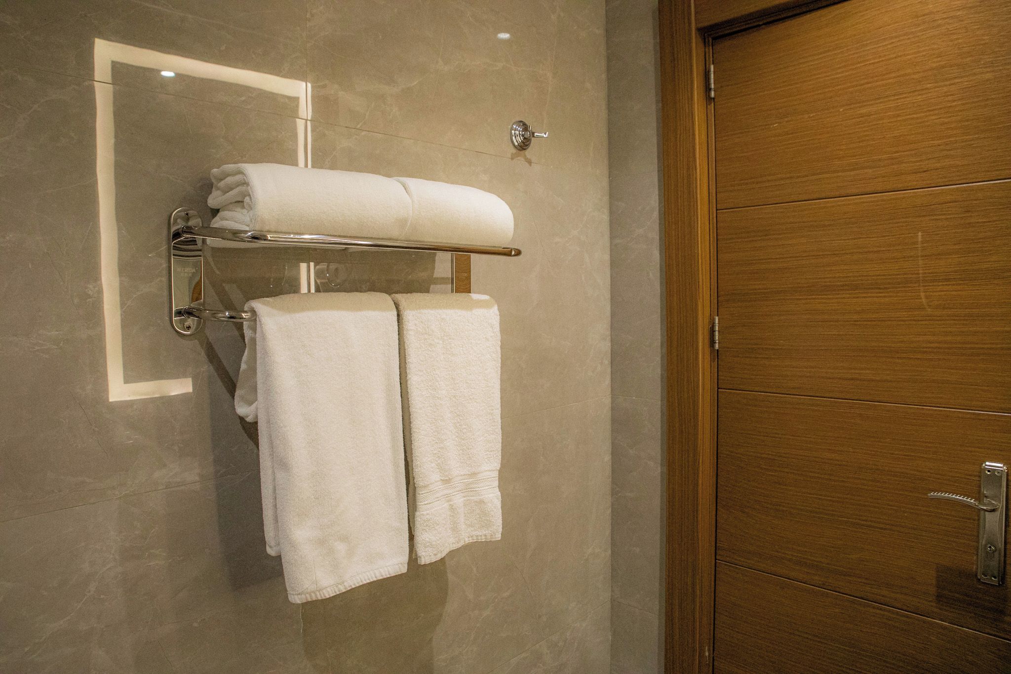 Ein Badezimmer mit Holztür, Handtuchhalter und zwei Handtüchern sowie einem Spiegel.