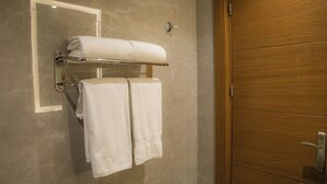 Un baño con puerta de madera, un perchero con dos toallas y un espejo.