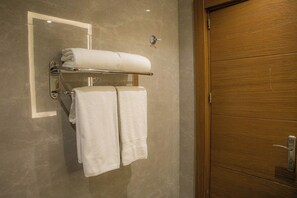 Ein Badezimmer mit Holztür, Handtuchhalter und zwei Handtüchern sowie einem Spiegel.