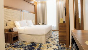 Una habitación de hotel con cama, mesita de noche, lámpara y espejo.