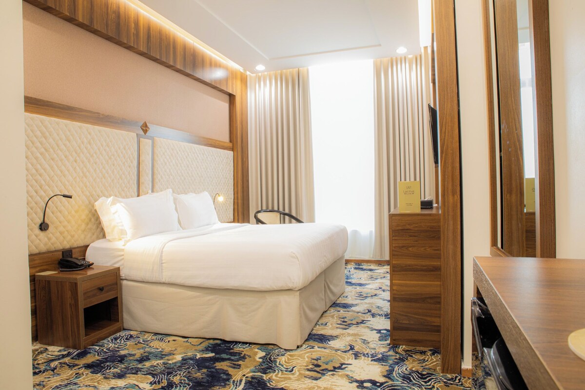 Ein Hotelzimmer mit Bett, Nachttisch, Lampe und Spiegel.