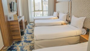 Habitación de hotel con dos camas, un escritorio, un espejo y una ventana con vista a la ciudad.