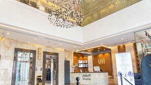 Zona de recepción de un hotel con suelo de m ármol, mostrador de recepción y una lámpara de araña moderna.