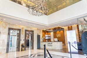 Ein Hotel-Empfangsbereich mit Marmorboden, einer Rezeption und einer modernen Kronleuchter.