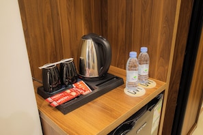 A kitchenette with a coffee maker, two water bottles, and two packets of Nescafe coffee. - Lavi Park Hotel (Makkah)