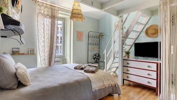 Ein Schlafzimmer mit Bett, Kommode, Fernseher und einem Fenster mit Vorhängen.