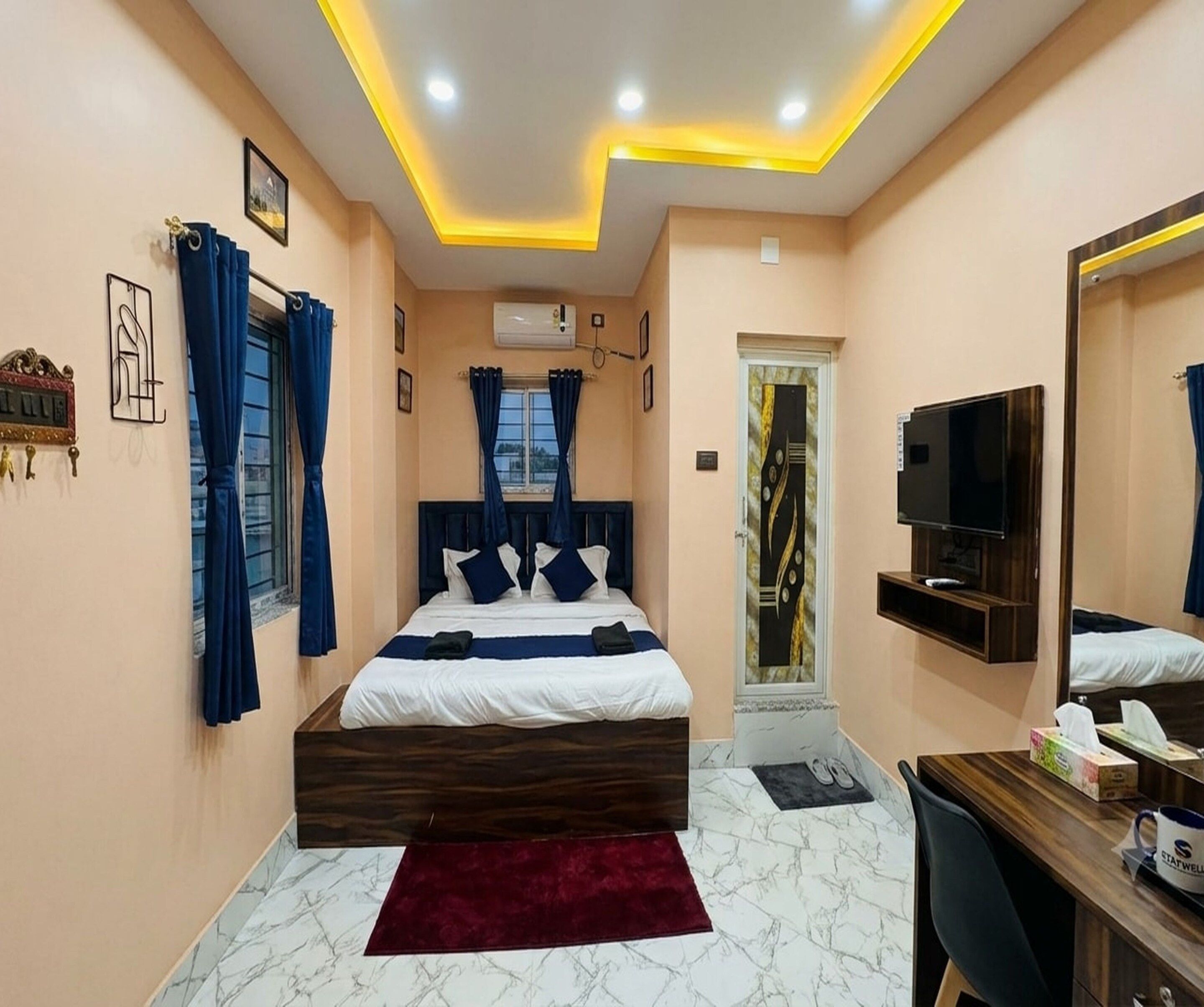 A hotel room with a bed, a desk, a TV, and a mirror.