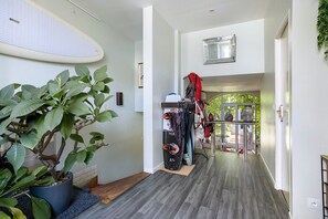 Passadís amb una planta en test, un penjallabecs amb borses i vista a una zona exterior.