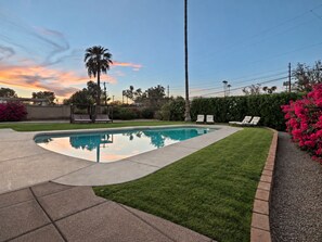 A swimming pool with a curved edge, surrounded by a well-maintained lawn and a brick border. - This house is a 3 bedroom(s), 2 bathrooms, located in Scottsdale, AZ. (Scottsdale)