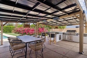 Eine Terrasse im Freien mit Grill, Sitzgelegenheiten und einem Pool.