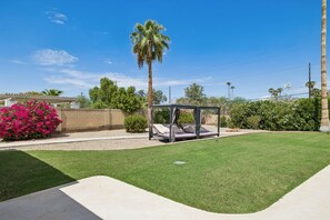 A well-maintained outdoor area with a grassy lawn, a covered seating area, and a variety of plants and trees. - This house is a 3 bedroom(s), 2 bathrooms, located in Scottsdale, AZ. (Scottsdale)