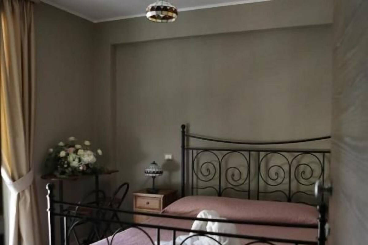 A bedroom with a metal bed frame, a hanging light fixture, and a bedside table with a lamp.