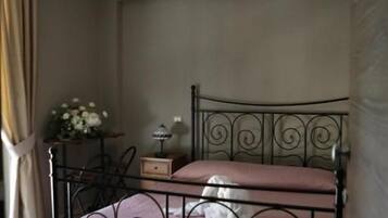 Quarto com estrutura de cama de metal, luminária pendente e mesa de cabeceira com abajur.