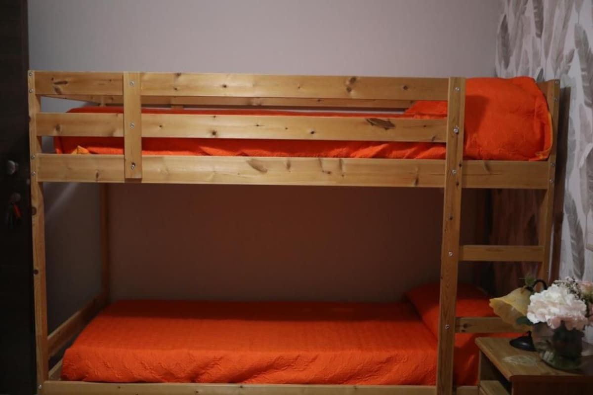 Kerrossänky, jossa on puinen runko ja oranssit vuodevaatteet.