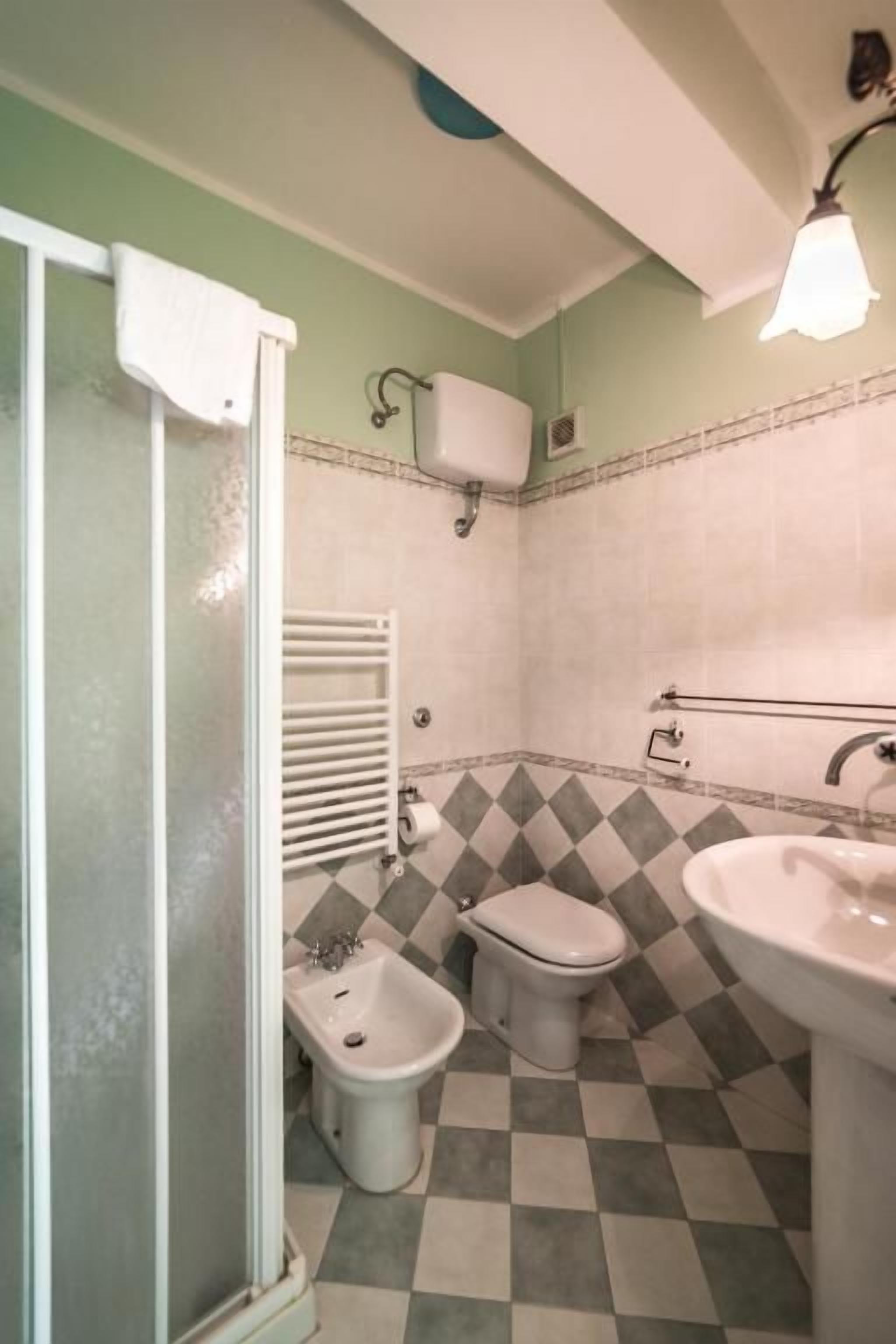 Un baño con ducha, inodoro, bidé y lavamanos.