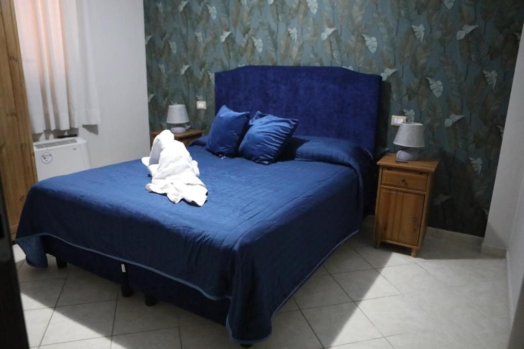 A bedroom with a large bed, two nightstands, and a wall with leaf patterns.