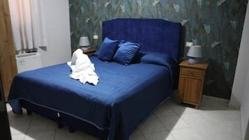 A bedroom with a large bed, two nightstands, and a wall with leaf patterns.