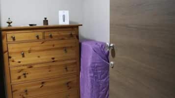 A room with a wooden dresser, a television mounted on the wall, and a door with a number.
