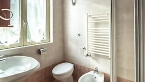 Une salle de bain équipée de toilettes, d’un bidet et d’un lavabo.