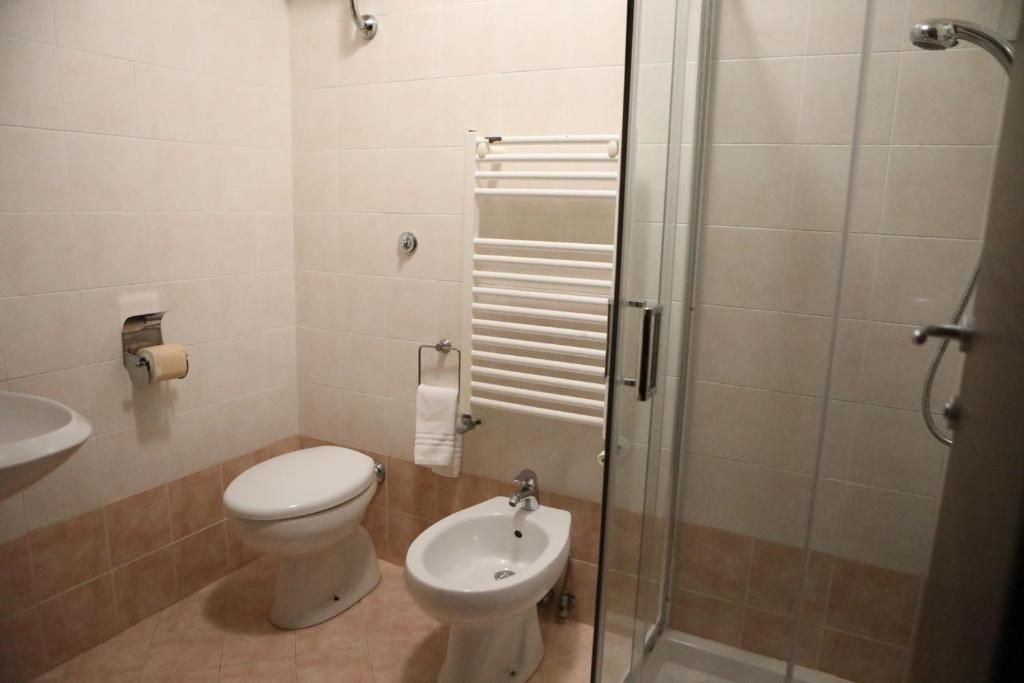Une salle de bain comprenant des toilettes, un bidet, un lavabo et une douche à parois de verre.