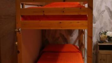 Un lit superposé avec un matelas orange dans une pièce dont le papier peint est à motifs.