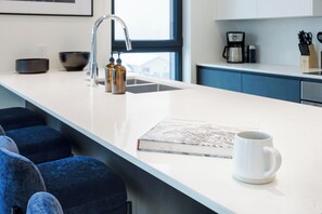 Eine moderne Küche mit weißer Arbeitsplatte, einer Kaffeemaschine und einem Buch.