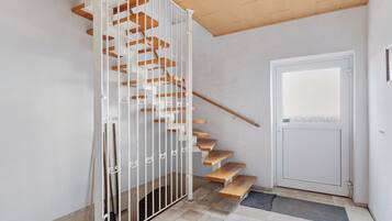 A staircase with wooden steps and white railings, leading to a door with a window.