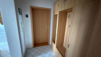 Een kamer met een houten garderobe, een deur en betegelde vloer.