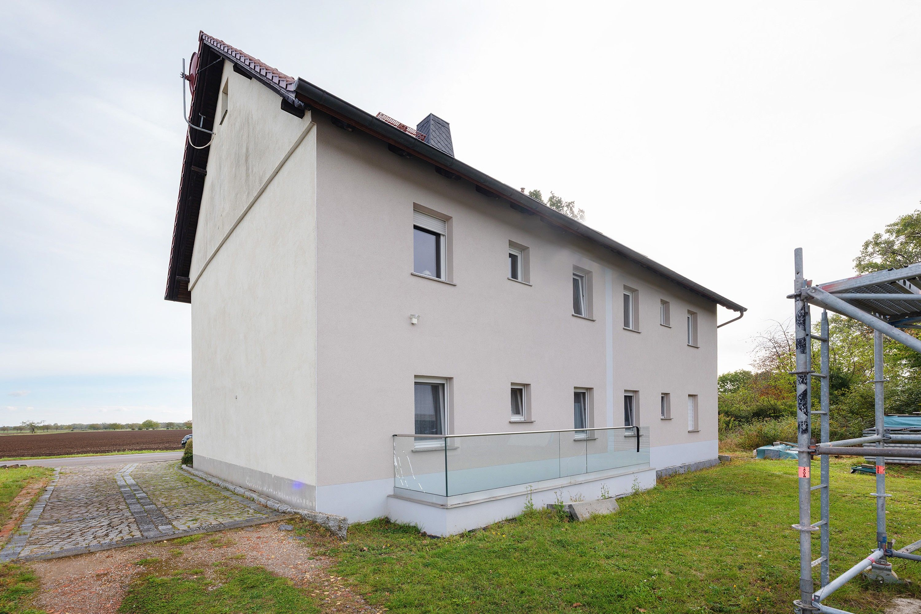A two-story building with a flat roof and a balcony.