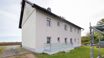 A two-story building with a flat roof and a balcony.