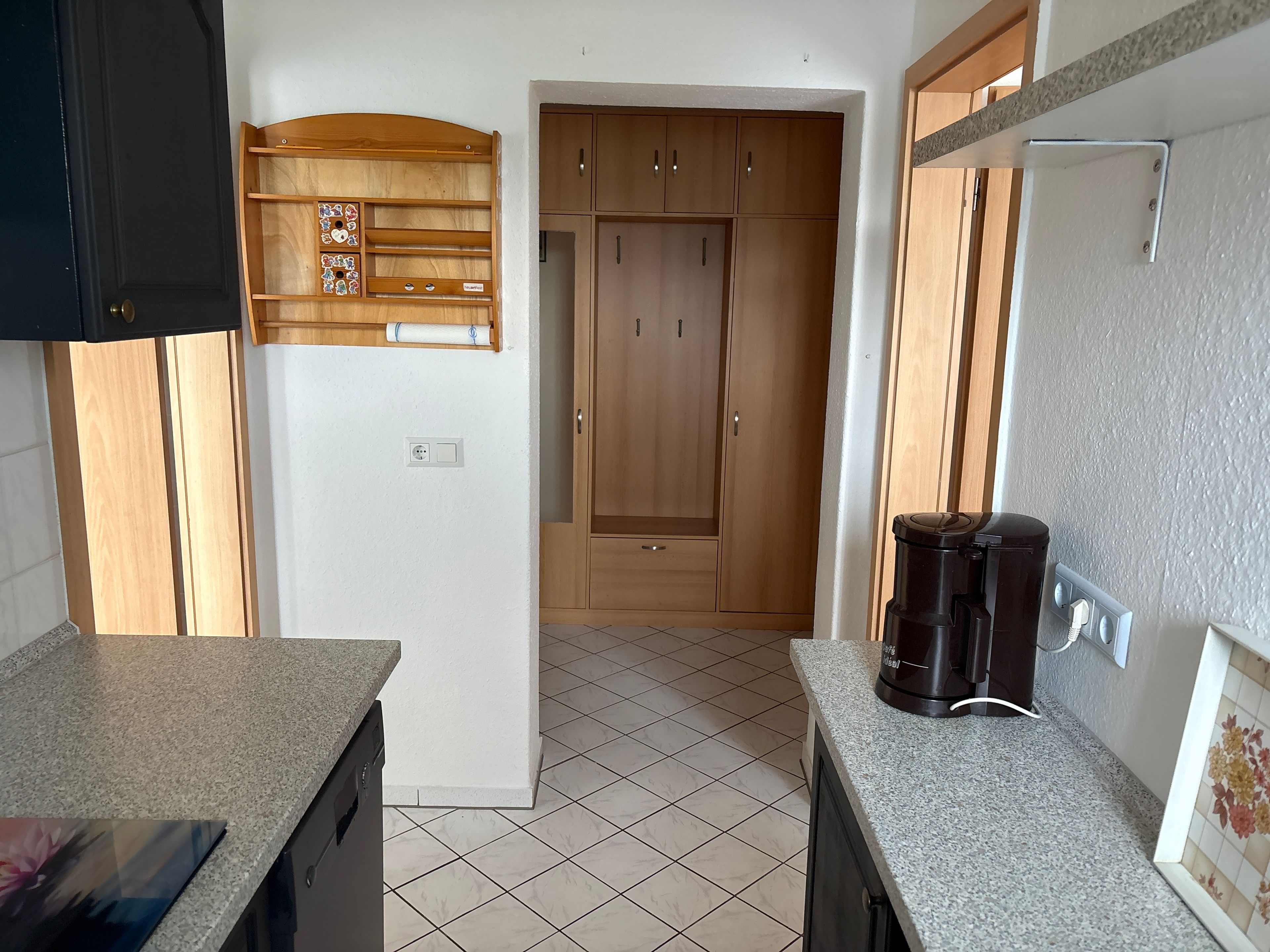 A kitchen with a countertop, a coffee maker, cabinets, and a power outlet.