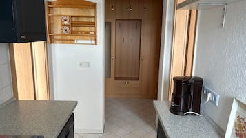 A kitchen with a countertop, a coffee maker, cabinets, and a power outlet.