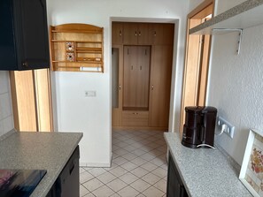 Cuina amb taulell, cafetera, armaris i presa elèctrica.