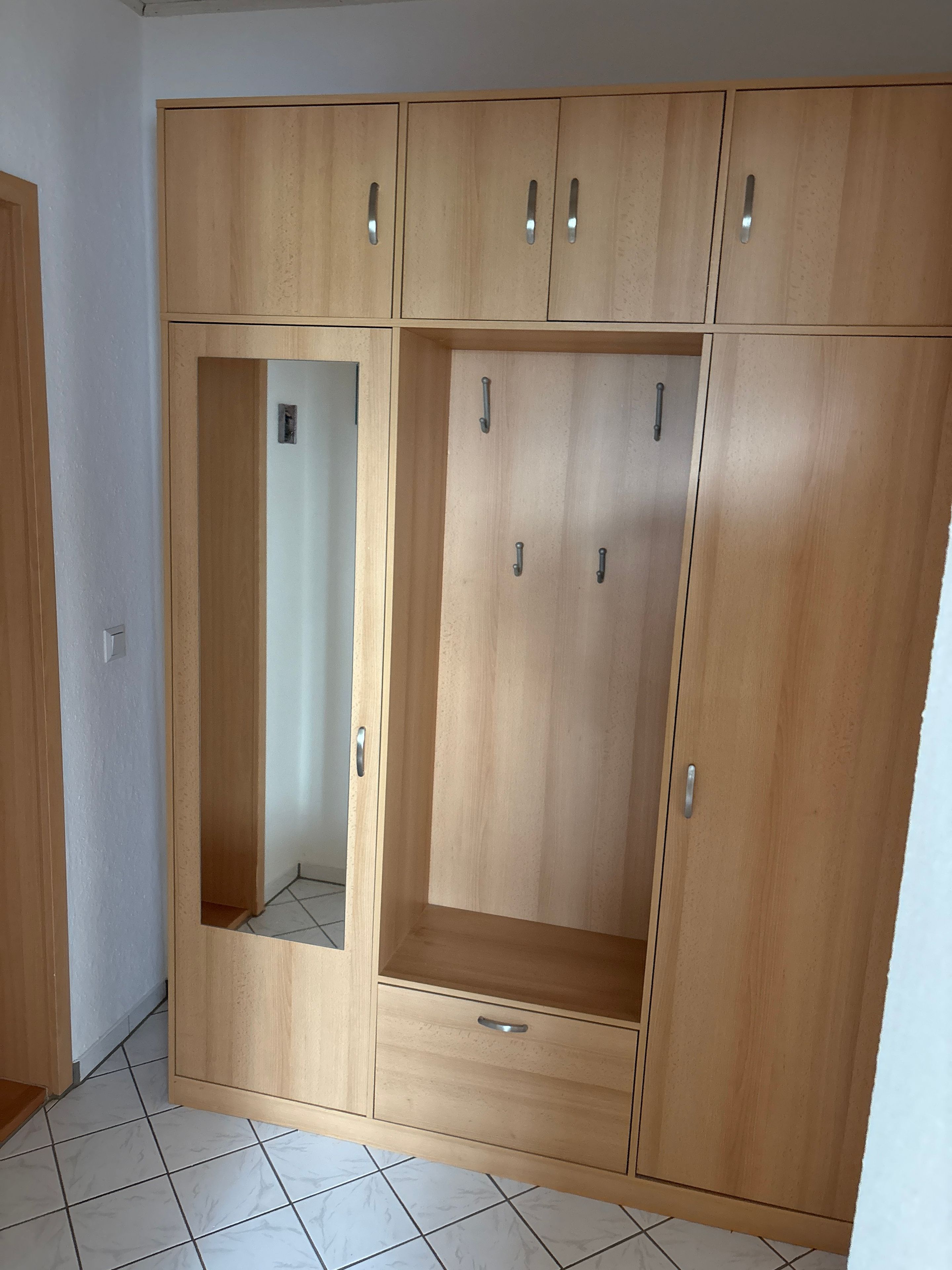 A wooden wardrobe with multiple compartments and handles.